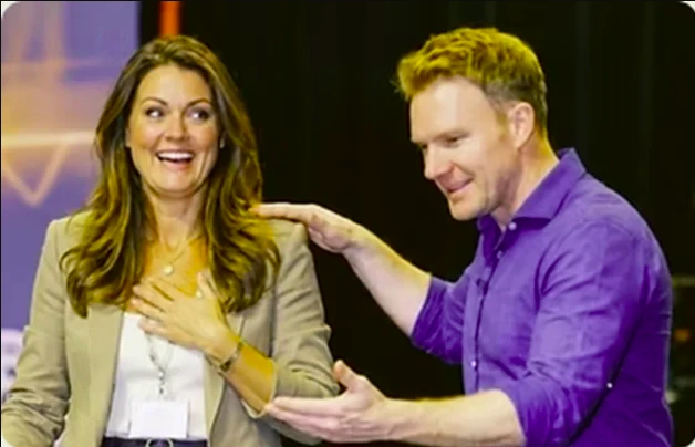 Richard Ford coaching a client who is smiling and surprised, hand on her chest