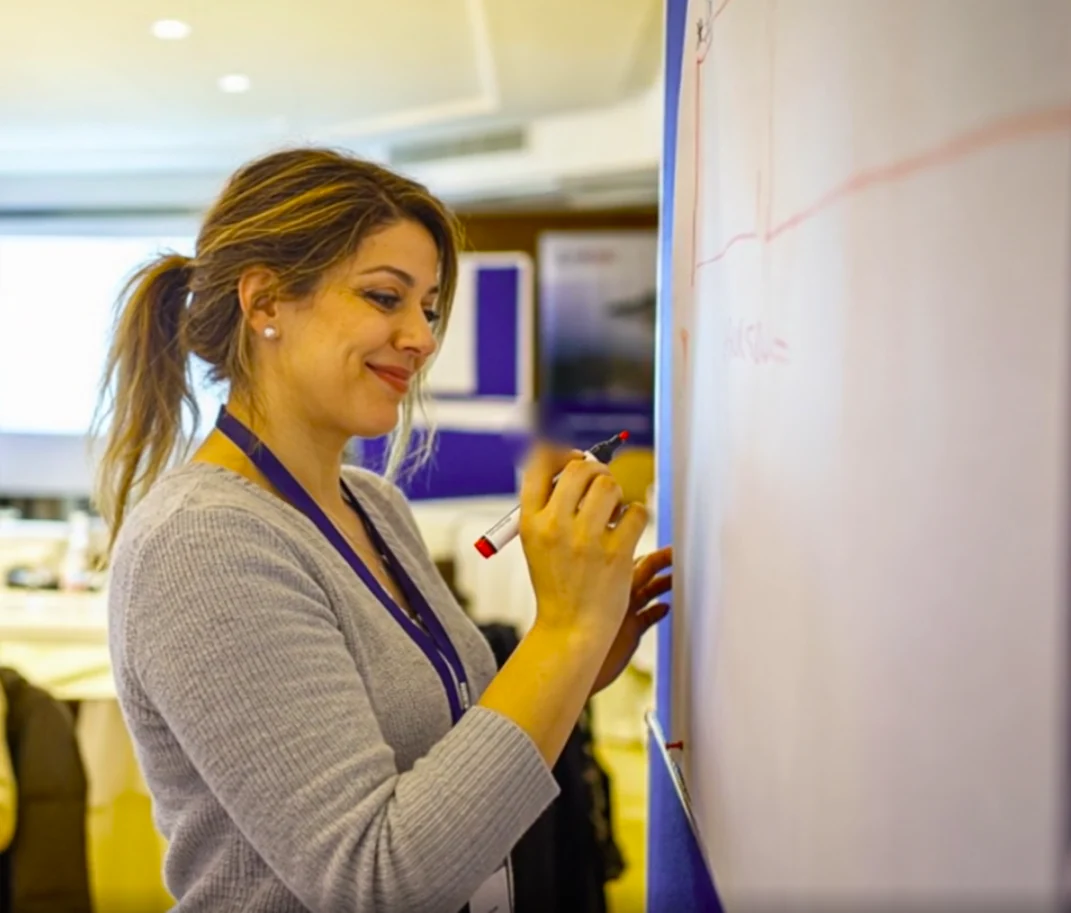 Jessica smiling as she writes on a flip chart during a workshop