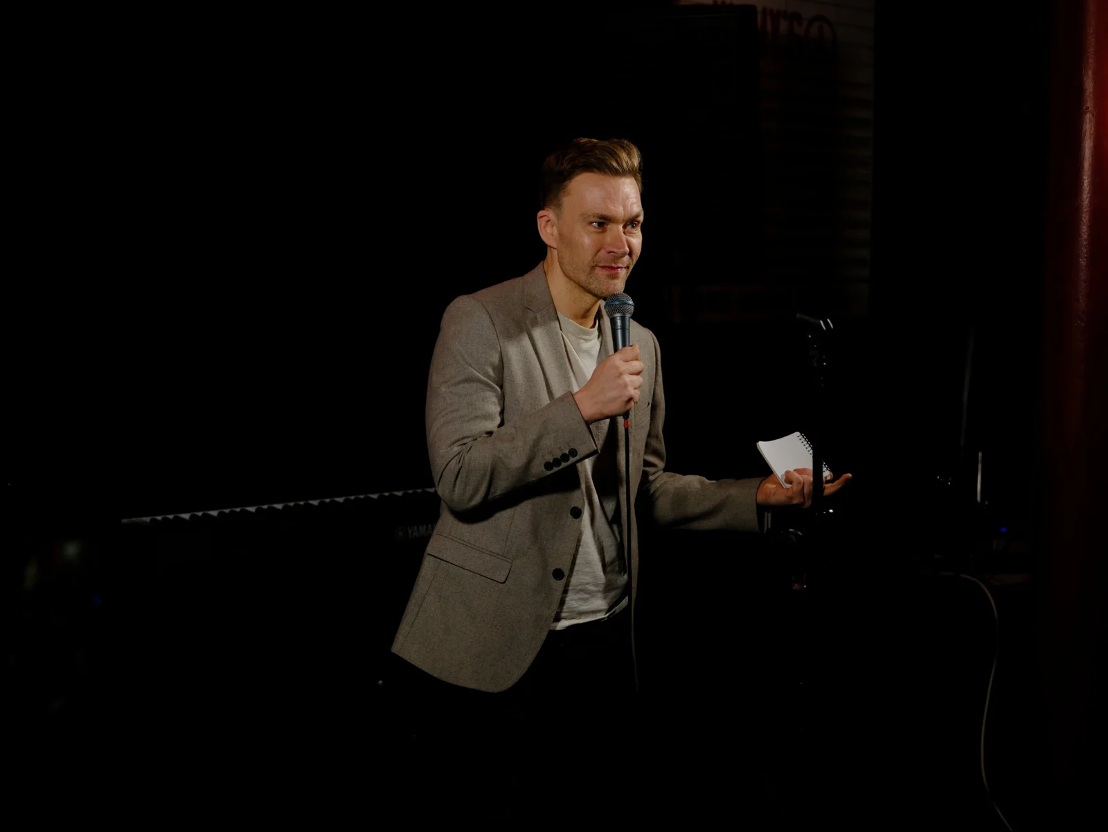 Richard speaking into a microphone on a dark stage