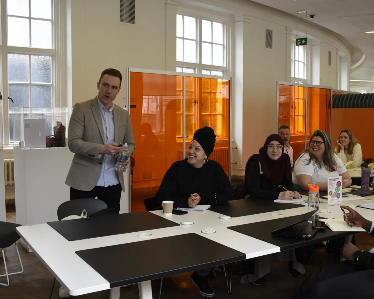 Richard standing and talking with a workshop group seated around a table