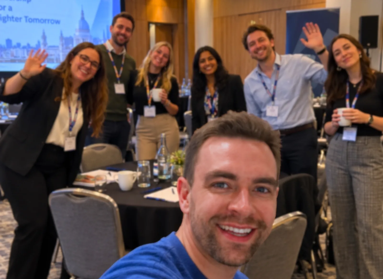 Richard taking a selfie with a smiling group waving behind him at a leadership workshop